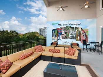 A patio with a couch and chairs and a mural on the wall